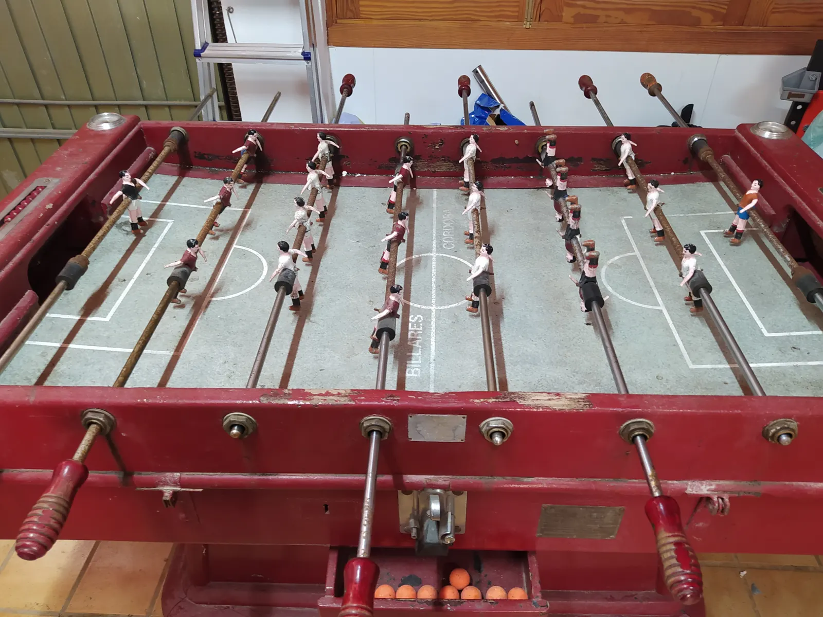 El mismo futbolín antes de restaurarlo, pintado de rojo y con los muñecos gastados